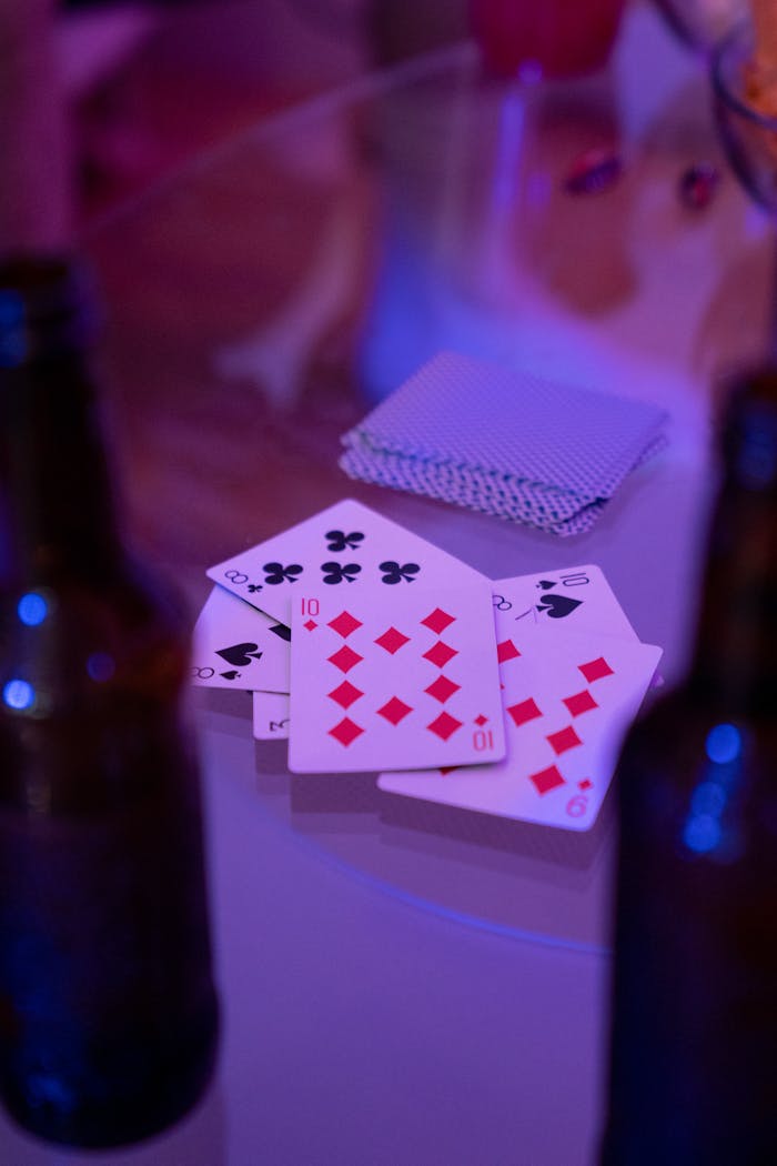 A vibrant setup of playing cards and beer bottles on a glass table, ideal for leisure and gaming concepts.